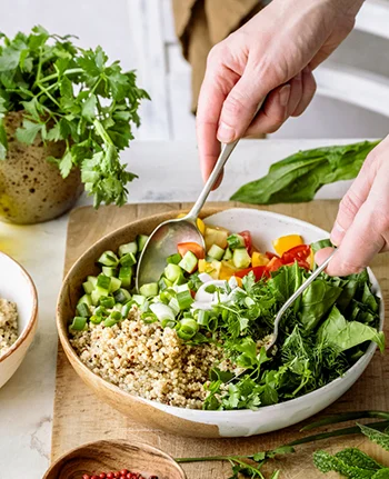 Veselīgs dzīvesveids – krāsains dārzeņu un kvinojas salātu šķīvis ar svaigiem zaļumiem.