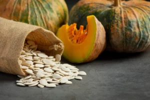 Ķirbju sēklas izbirušas no maisiņa blakus svaigam ķirbim – dabīgs veselīga uztura avots