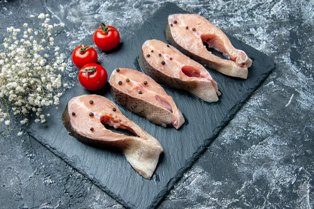 Svaigas laša šķēles uz melna akmens dēlīša ar pipariem – bagātīgs valīna avots.